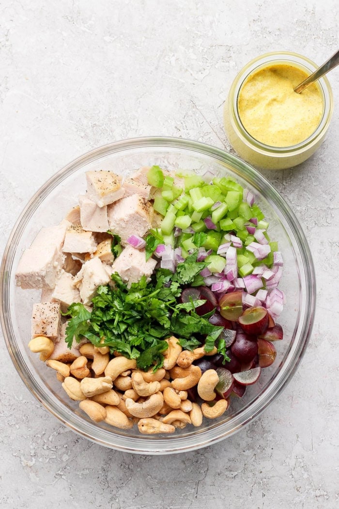 This easy Curry Chicken Salad recipe is the perfect blend of sweet and savory, with juicy grapes, cashews, and a creamy curried dressing. Overhead view of curry chicken salad ingredients in bowl before adding dressing