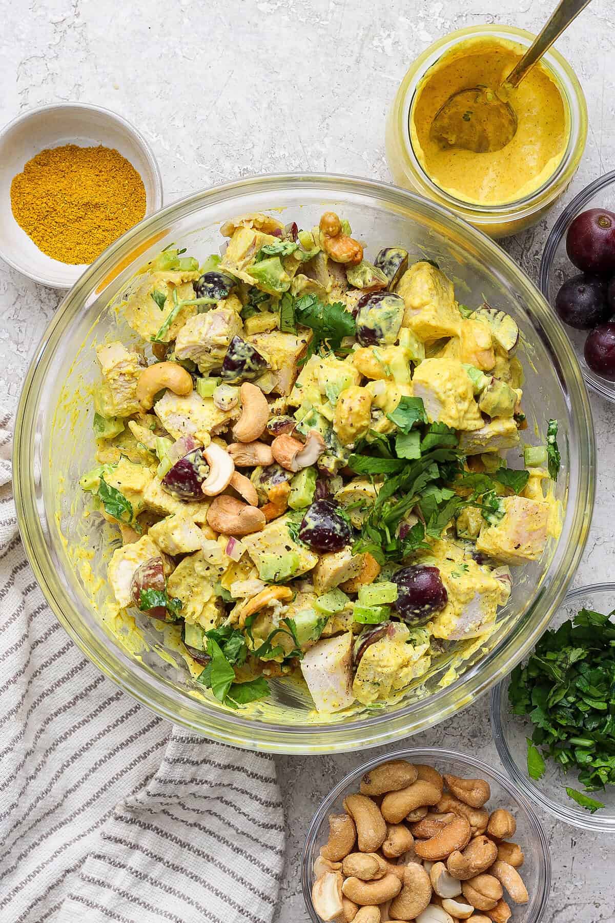 Bowl of curry chicken salad surrounded by smaller bowls of ingredients