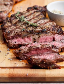 Sliced grilled ribeye steak on cutting board.