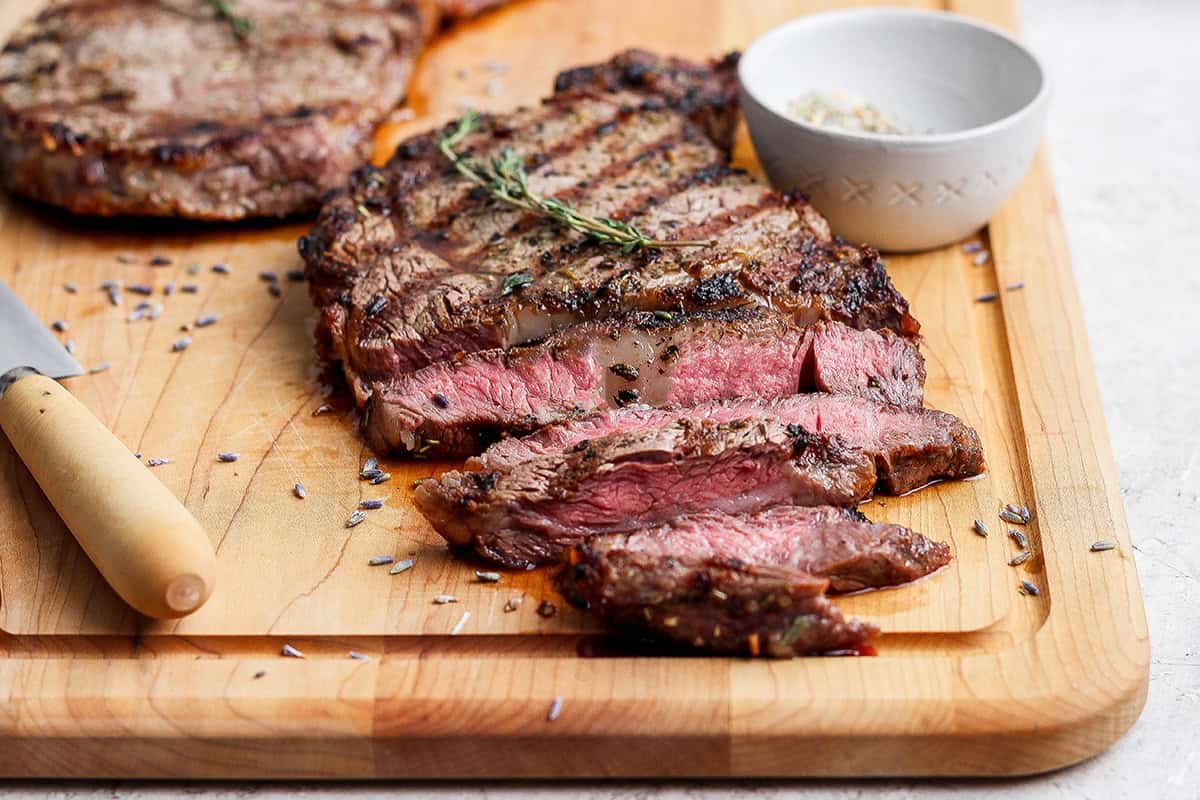 This Grilled Ribeye Recipe will show you the secret to perfectly grilled steak every time! It's tender, juicy, and packed with savory flavor. Sliced grilled ribeye steak on cutting board.