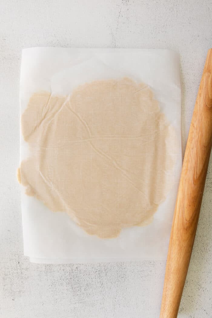 This rustic apple galette has warm cinnamon apples, a buttery crust, and an almond caramel drizzle. It's quicker and easier than apple pie! Pastry dough rolled between parchment paper