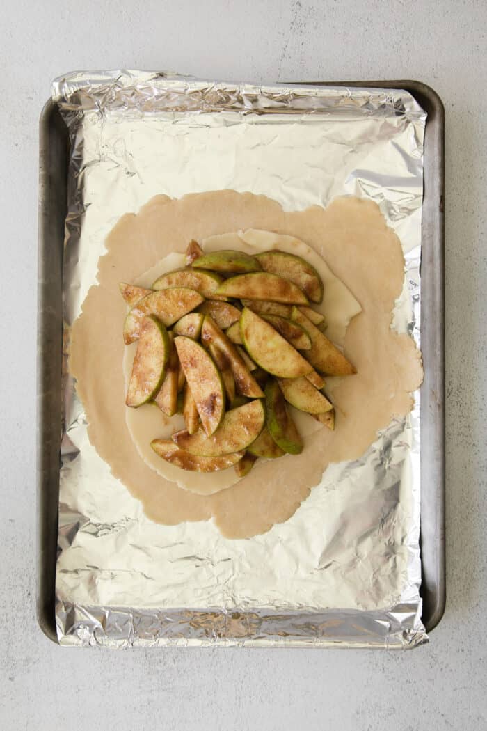 This rustic apple galette has warm cinnamon apples, a buttery crust, and an almond caramel drizzle. It's quicker and easier than apple pie! Apple filling on top of pastry dough