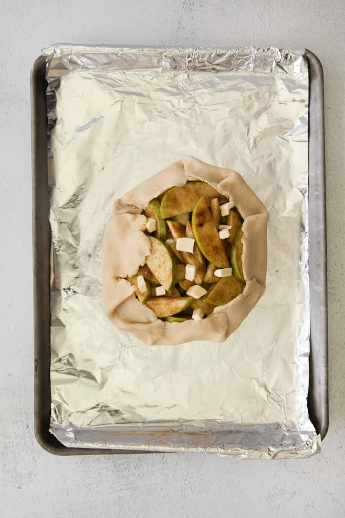 This rustic apple galette has warm cinnamon apples, a buttery crust, and an almond caramel drizzle. It's quicker and easier than apple pie! Unbaked apple almond galette ready to bake