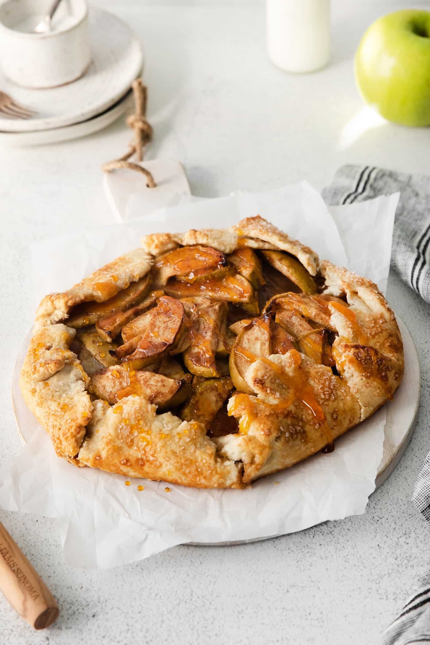 This rustic apple galette has warm cinnamon apples, a buttery crust, and an almond caramel drizzle. It's quicker and easier than apple pie! Apple galette on a serving tray