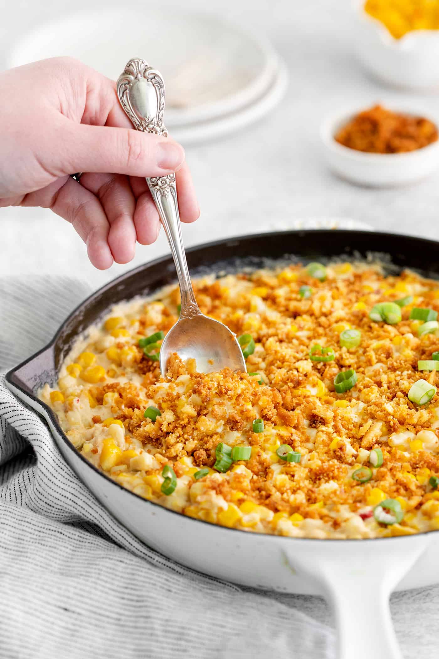 With 3 types of corn and a creamy Swiss cheese sauce, this Cheesy Skillet Scalloped Corn is a family favorite side dish! A spoon serving skillet corn