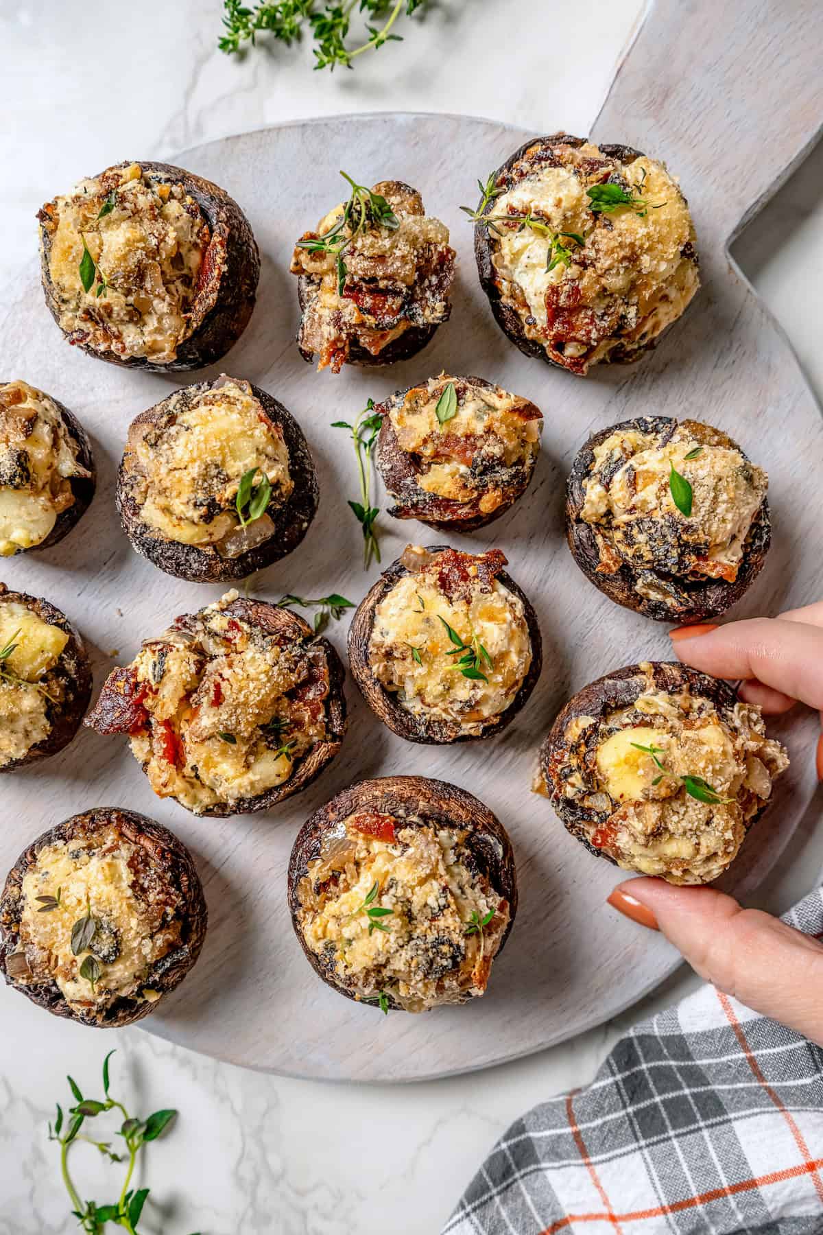 Hand pulling stuffed mushroom from serving board