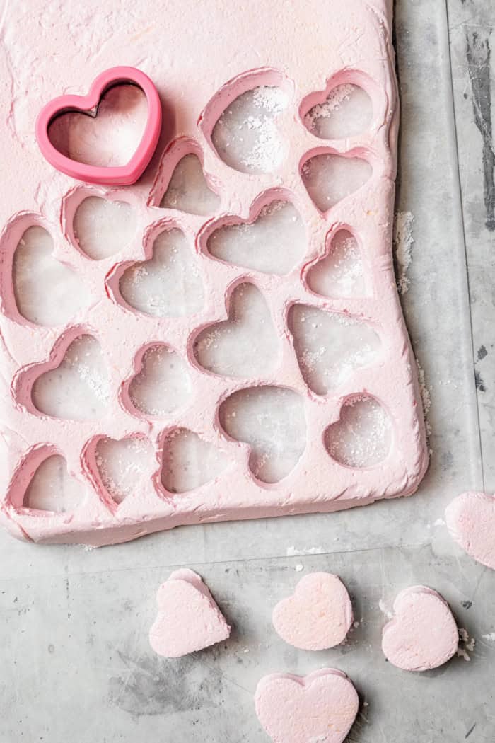 Homemade Marshmallow Hearts are the very best way to send a little love on Valentine’s Day — or any time of year. Fluffy, puffy, and sweet! Overhead view showing marshmallow hearts being cut
