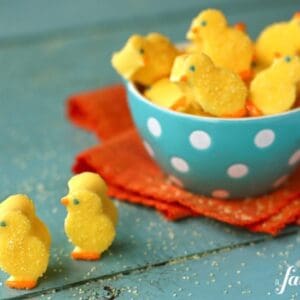 Yellow marshmallow chicks sprinkled with sugar in a blue bowl