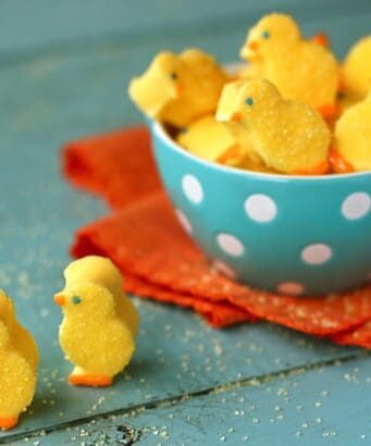 Yellow marshmallow chicks sprinkled with sugar in a blue bowl