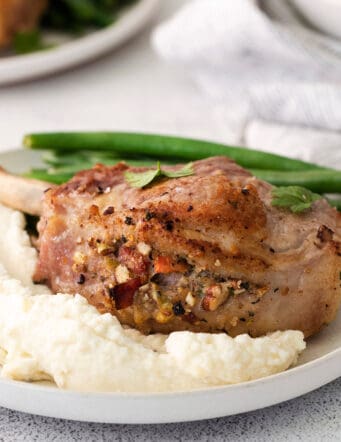 A plate of stuffed pork chops with mashed potatoes and green beans