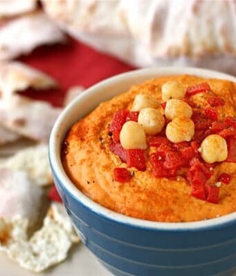a bowl of red pepper hummus and pita bread