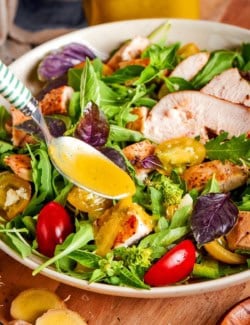 Spooning ginger dressing onto salad.