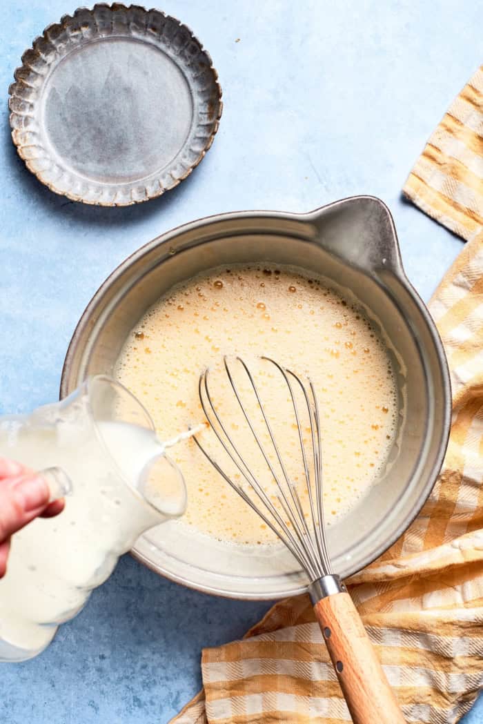 Pouring milk into mixing bowl with eggs
