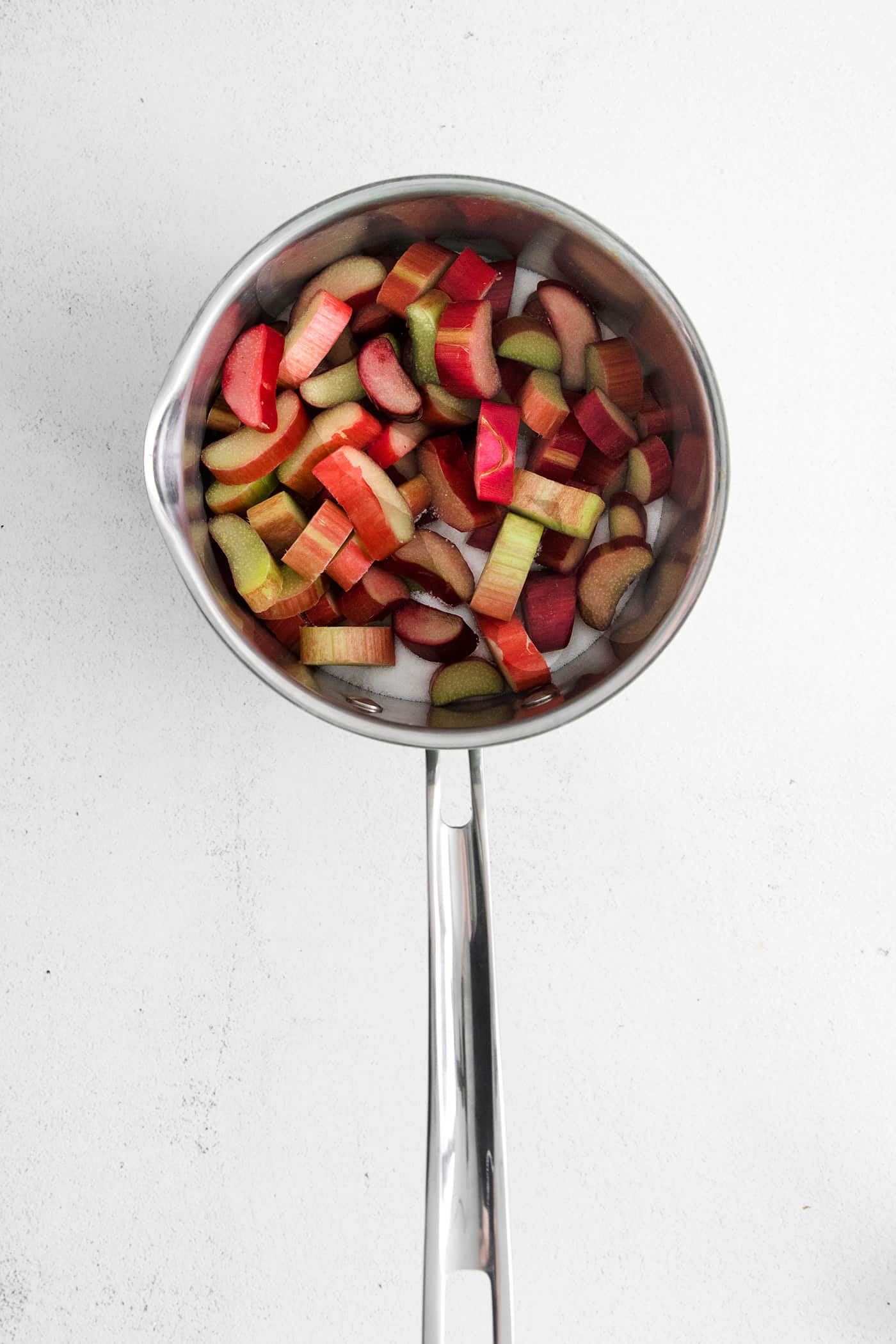 With a sweet-tart flavor, Ruby Rhubarb Syrup is just the thing for the best cocktails and mocktails, not to mention as a topping for pancakes and desserts! Pieces of rhubarb and water in a saucepan