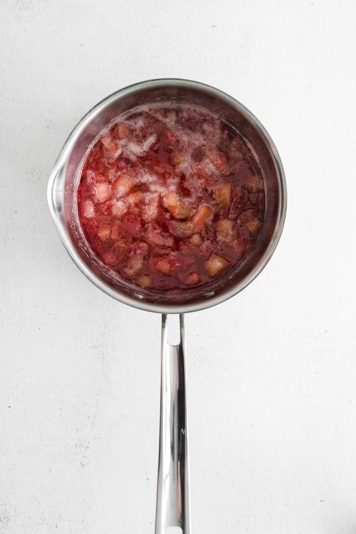 With a sweet-tart flavor, Ruby Rhubarb Syrup is just the thing for the best cocktails and mocktails, not to mention as a topping for pancakes and desserts! Softened pieces of rhubarb in a sauce pan