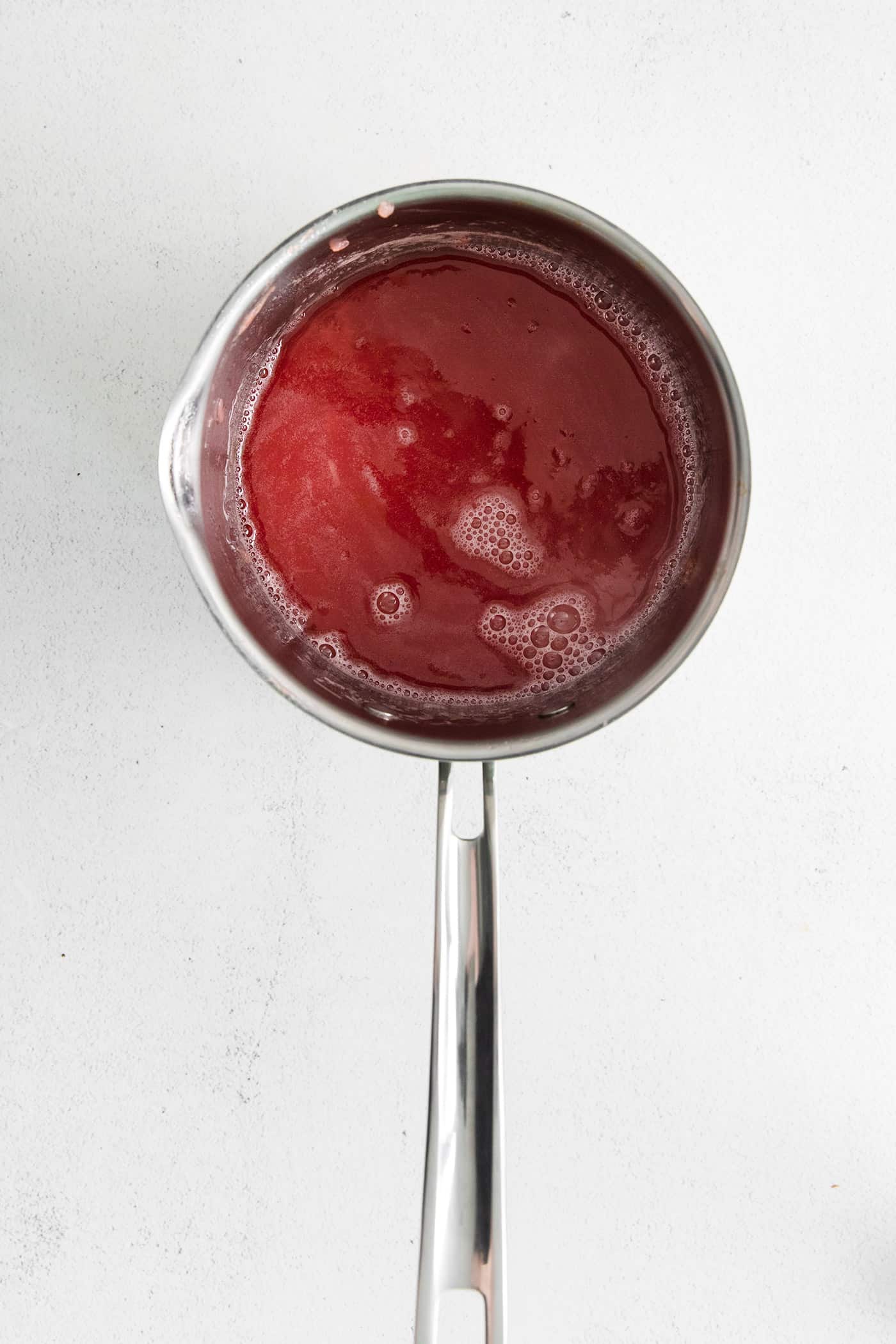 With a sweet-tart flavor, Ruby Rhubarb Syrup is just the thing for the best cocktails and mocktails, not to mention as a topping for pancakes and desserts! Rhubarb simple syrup in a saucepan