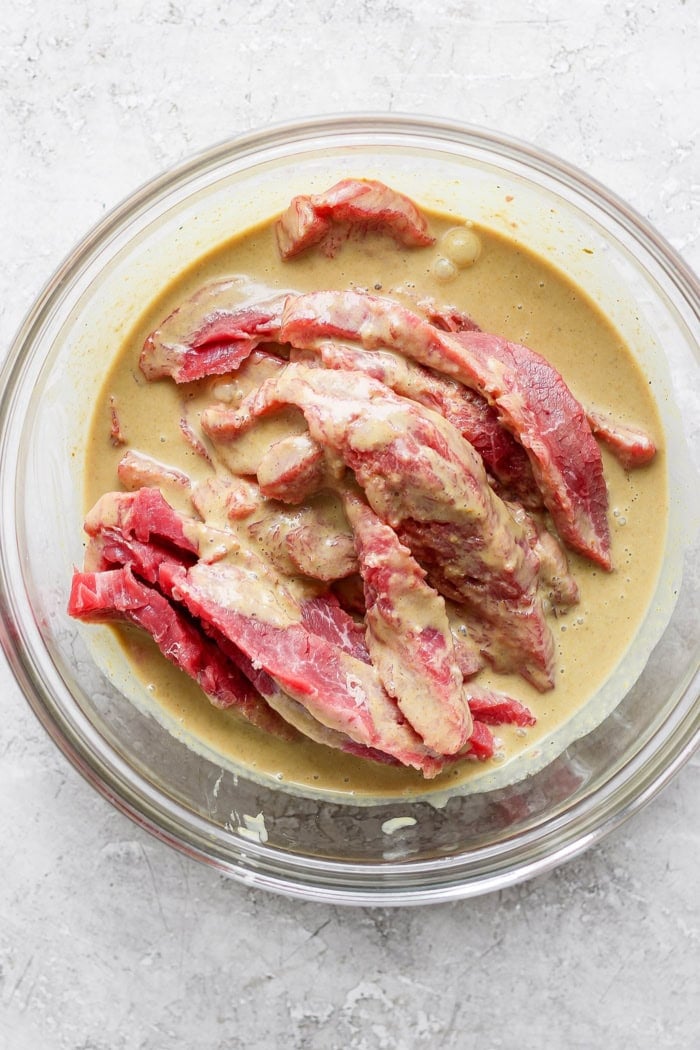 Tender beef is marinated in coconut milk, threaded onto skewers, and grilled to perfection in this coconut beef satay recipe. So flavorful! Sliced beef marinating in coconut milk mixture