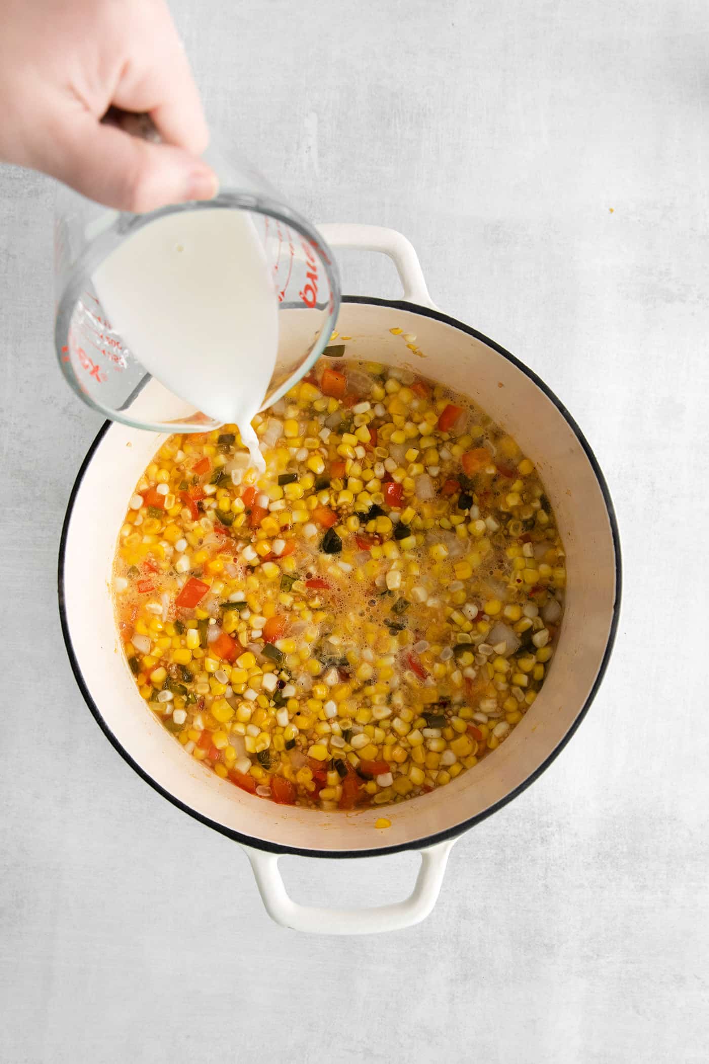Made with fresh sweet corn, peppers, and onion this Zesty Sweet Corn Relish is just what you need to spice up dishes from tacos to burgers. Cornstarch slurry being added to corn relish in a big pot