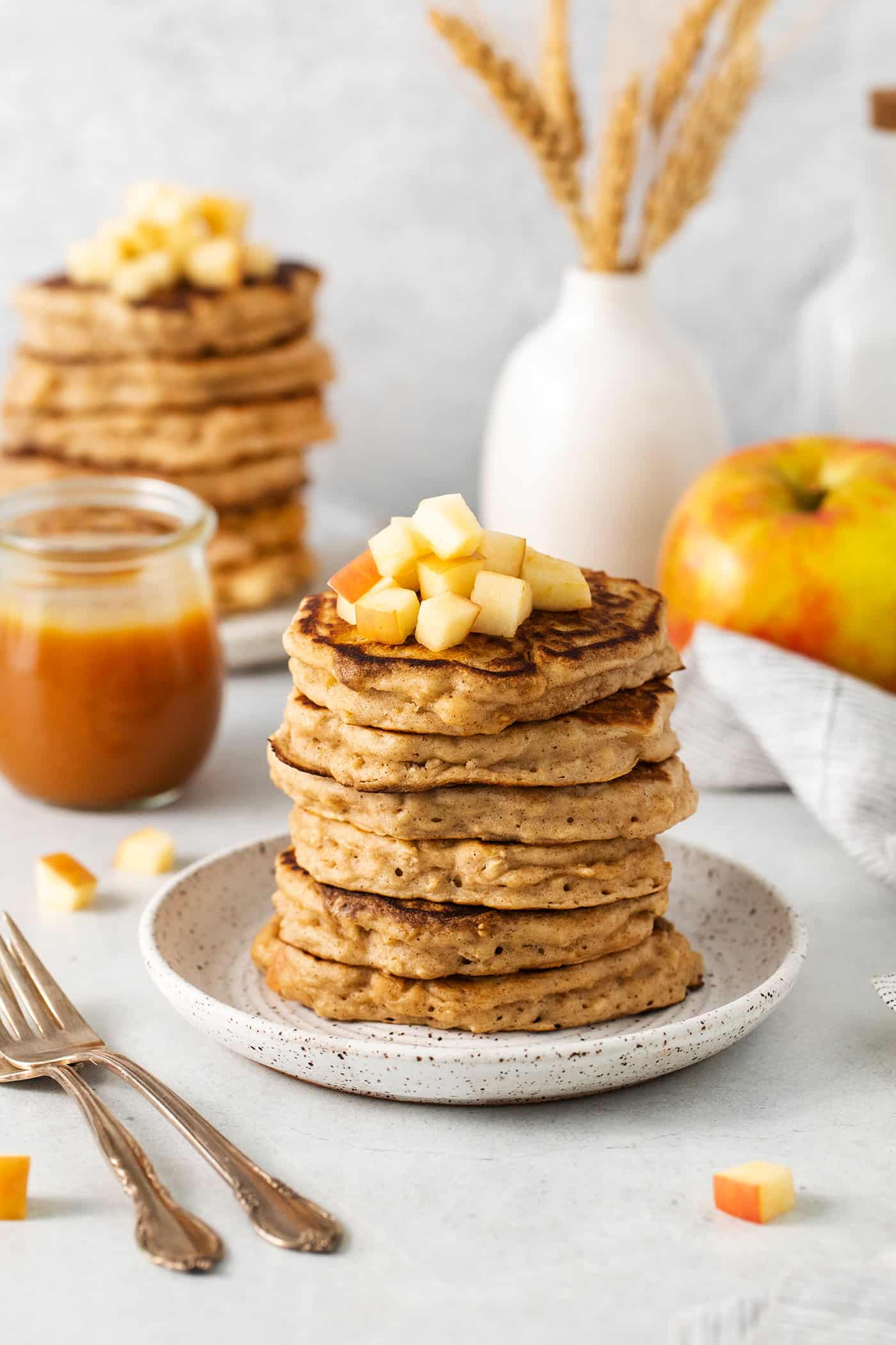 Studded with bits of apple and oats, these Apple Oatmeal Pancakes are a cozy, comforting breakfast that's hearty yet not heavy. Angled view of a stack of apple oatmeal pancakces