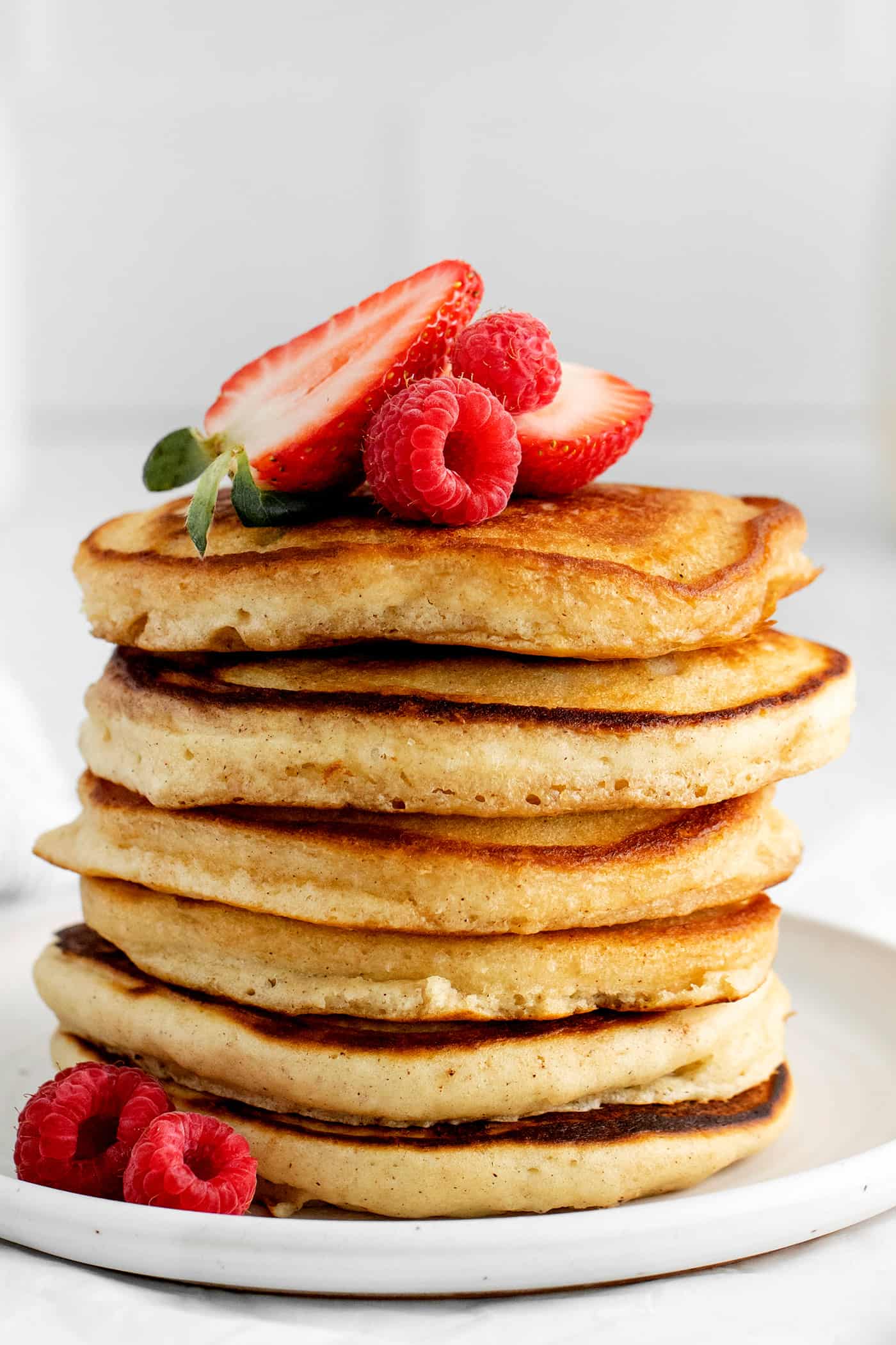 Made with pantry staples, these Buttermilk Pancakes are simply the best homemade pancakes you'll ever make! Super fluffy! A stack of buttermilk pancakes topped with strawberries