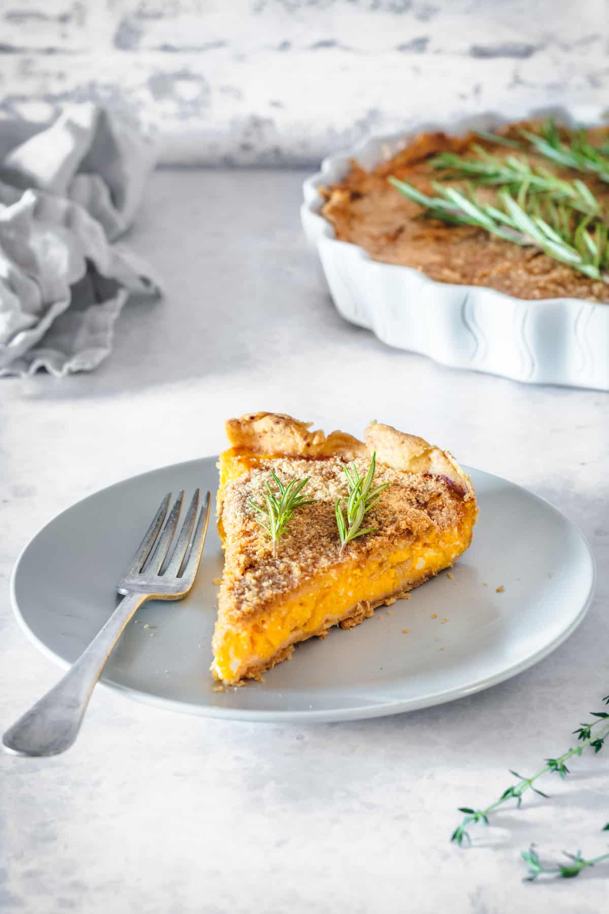 A slice of butternut squash tart with caramelized onions on a white plate