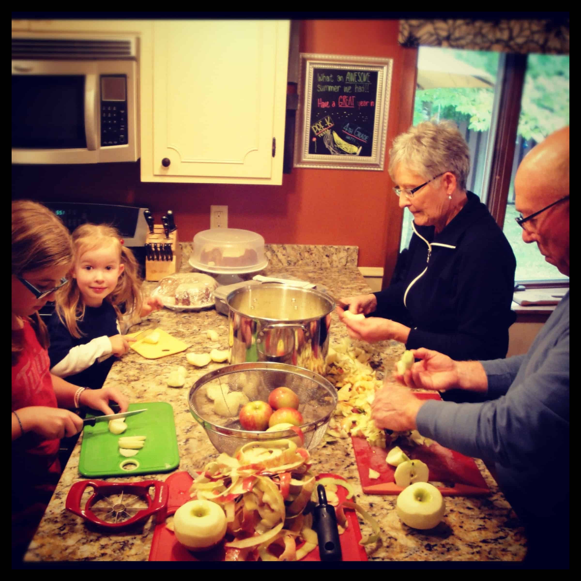 This easy homemade applesauce recipe can be made smooth or chunky, with simple refrigerator storage or canning for long-term pantry storage! family making applesauce together in kitchen