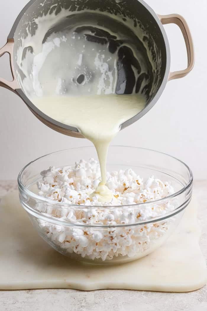 These easy Marshmallow Popcorn Balls are sweet and salty, crunchy and chewy, like a Rice Krispie treat made with popcorn instead of cereal! Pouring marshmallow mixture into bowl of popcorn.