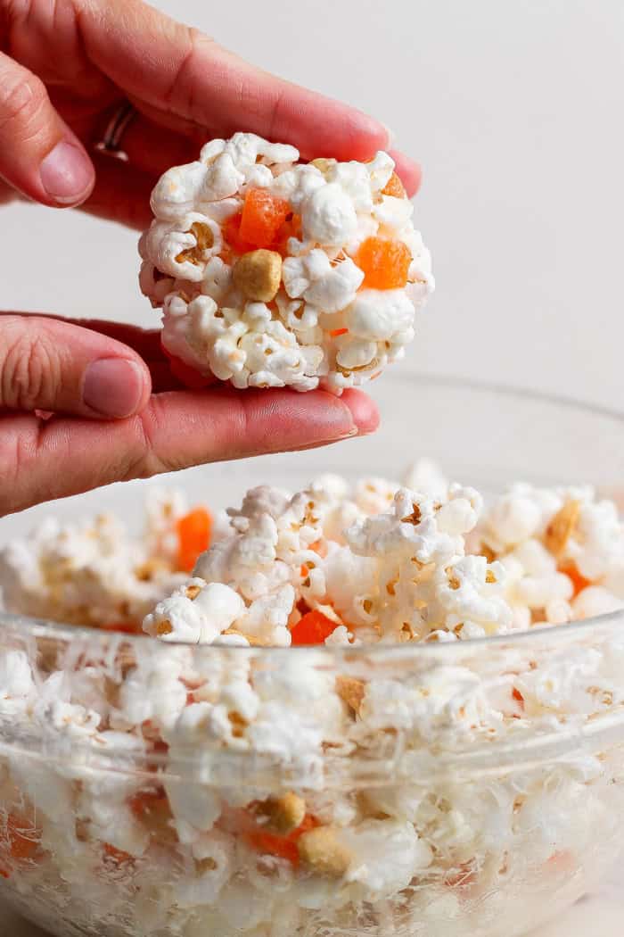 These easy Marshmallow Popcorn Balls are sweet and salty, crunchy and chewy, like a Rice Krispie treat made with popcorn instead of cereal! Hands rolling marshmallow popcorn ball.