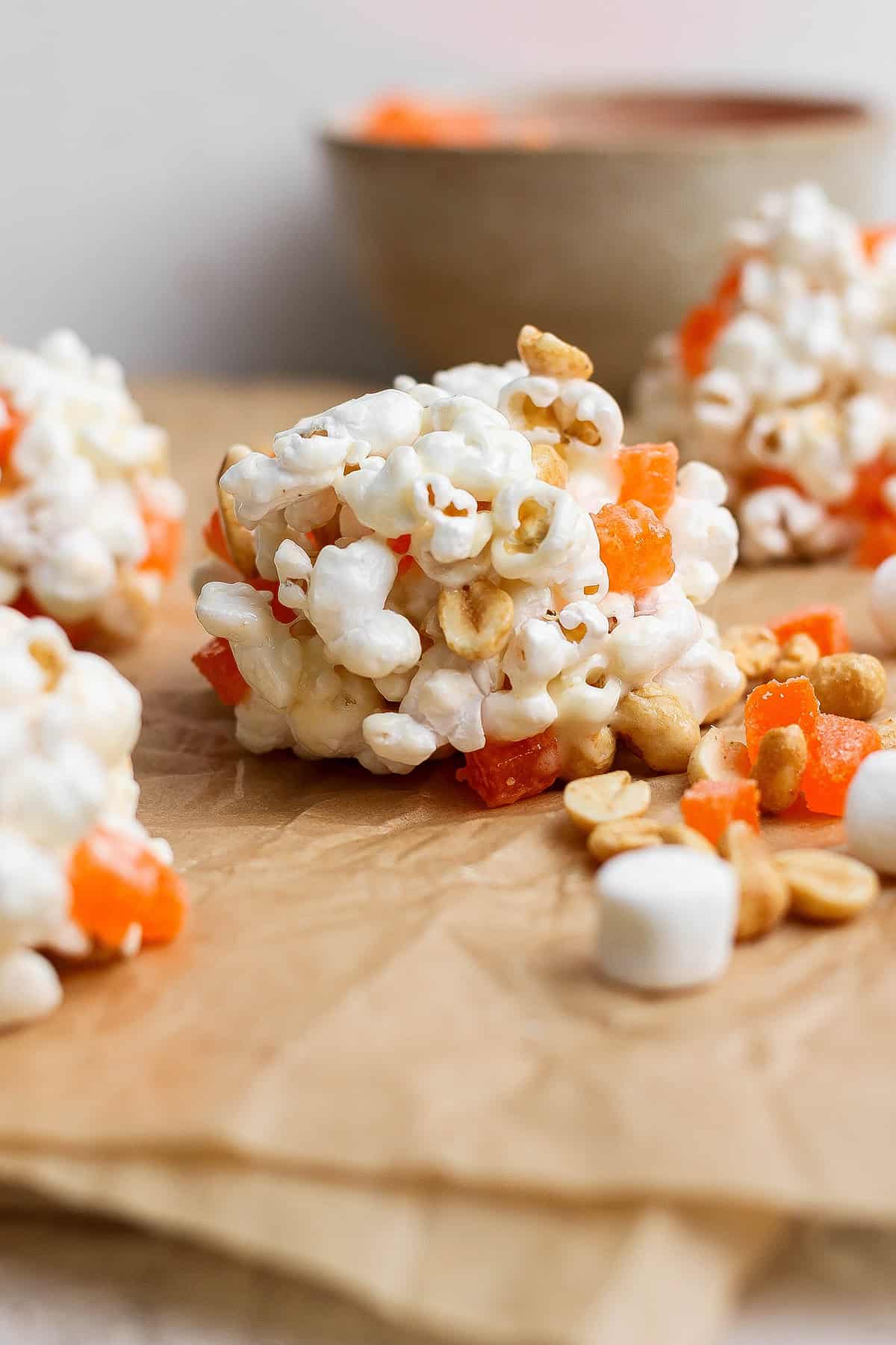 These easy Marshmallow Popcorn Balls are sweet and salty, crunchy and chewy, like a Rice Krispie treat made with popcorn instead of cereal! Marshmallow popcorn ball made with peanuts and orange gumdrops.