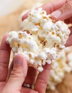 Hand pulling apart chewy marshmallow popcorn ball.