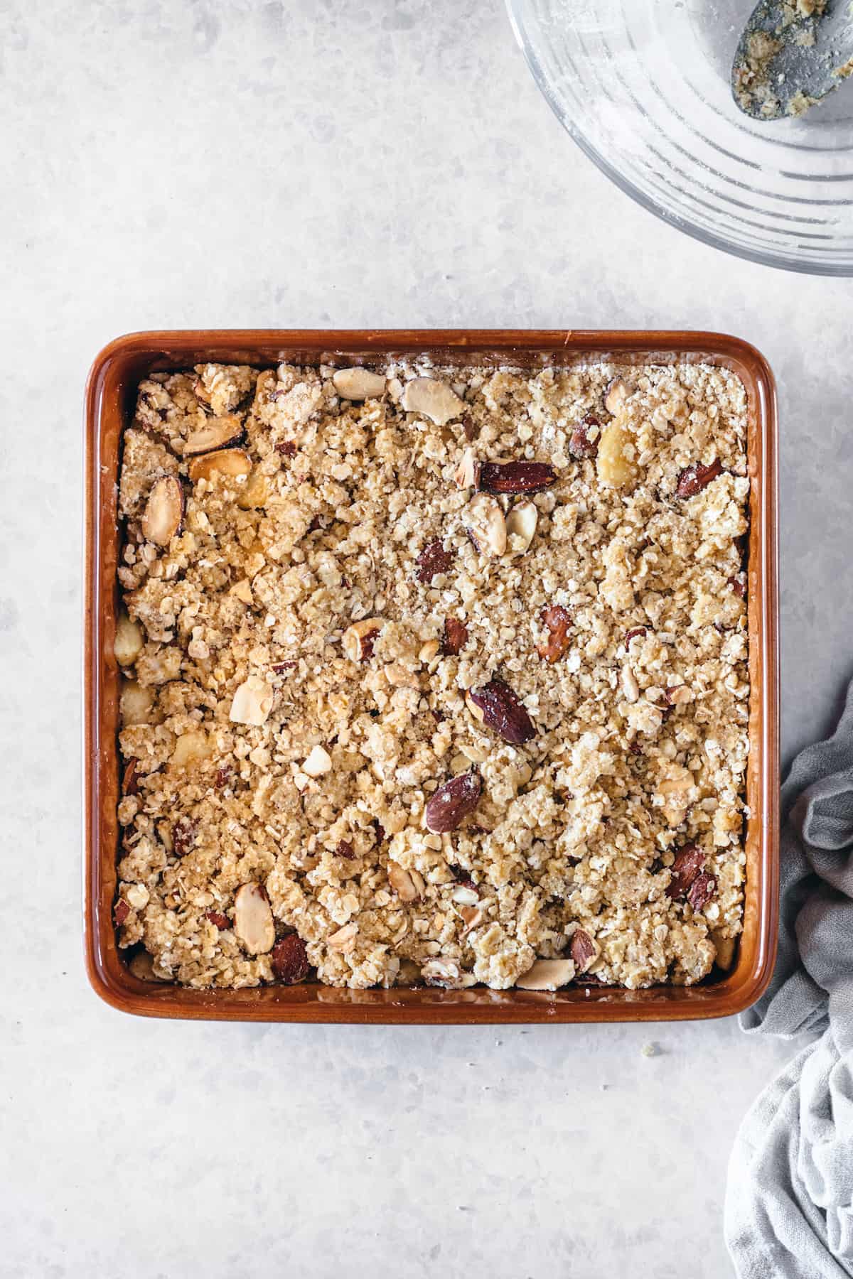 Unbaked caramel apple crisp with an oat almond topping in a baking dish