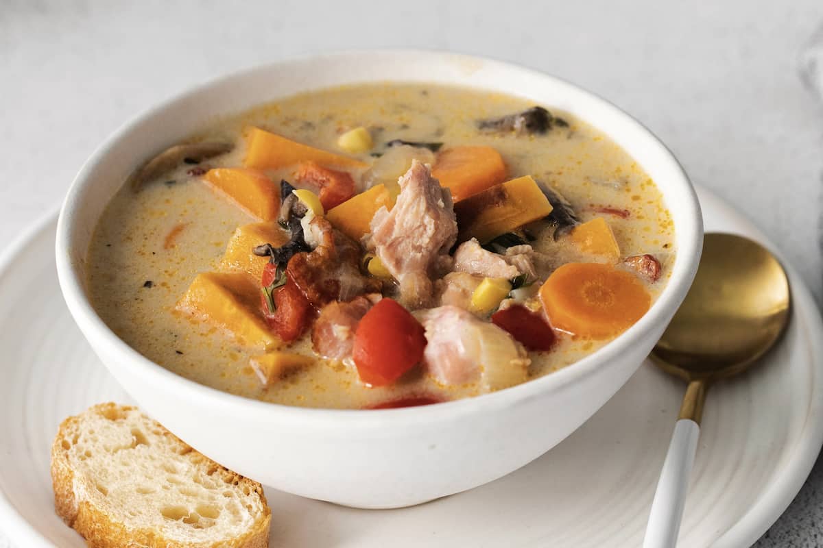 Make this easy Smoked Turkey Chowder recipe in one pot. It's lightly creamy and loaded with flavor, a great way to use up turkey leftovers! Close up of a bowl of smokedturkey chowder with a piece of crusty bread