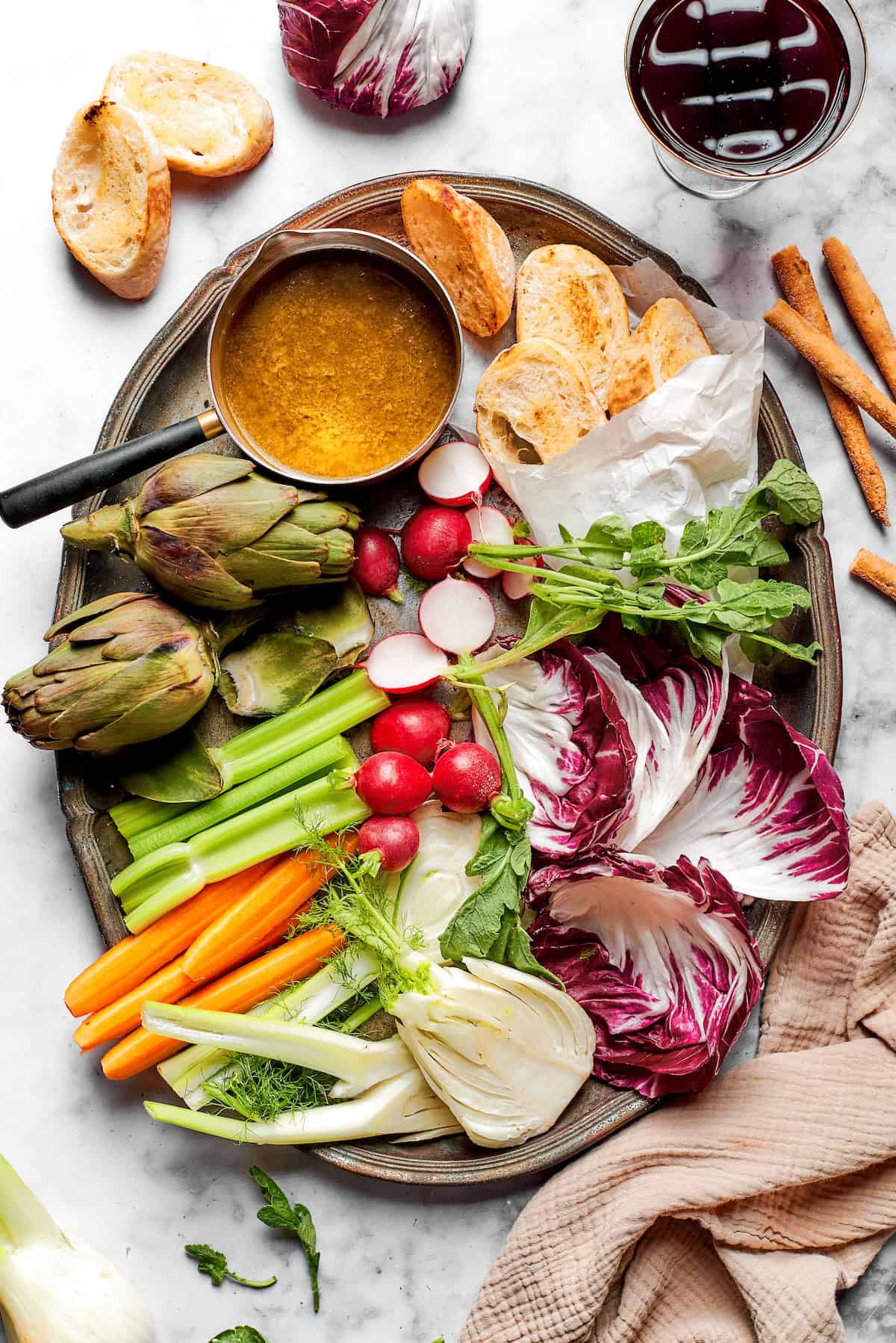 This Bagna Cauda dip is packed full of garlic and anchovies for big flavor — and it's loads of fun to eat! Easy to make in just 30 minutes! Overhead view of platter with bagna cauda, vegetables, and bread