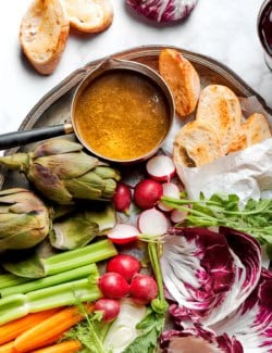 Bagna cauda in pan on tray with fresh vegetables and sliced bread