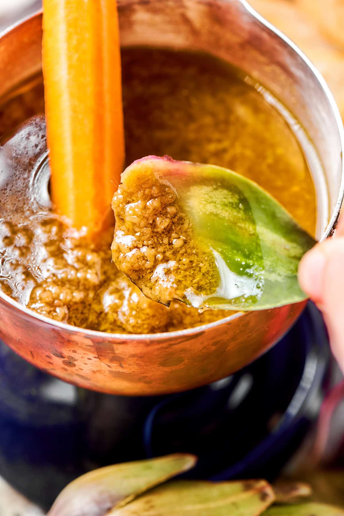 This Bagna Cauda dip is packed full of garlic and anchovies for big flavor — and it's loads of fun to eat! Easy to make in just 30 minutes! Hand holding artichoke leaf with bagna cauda