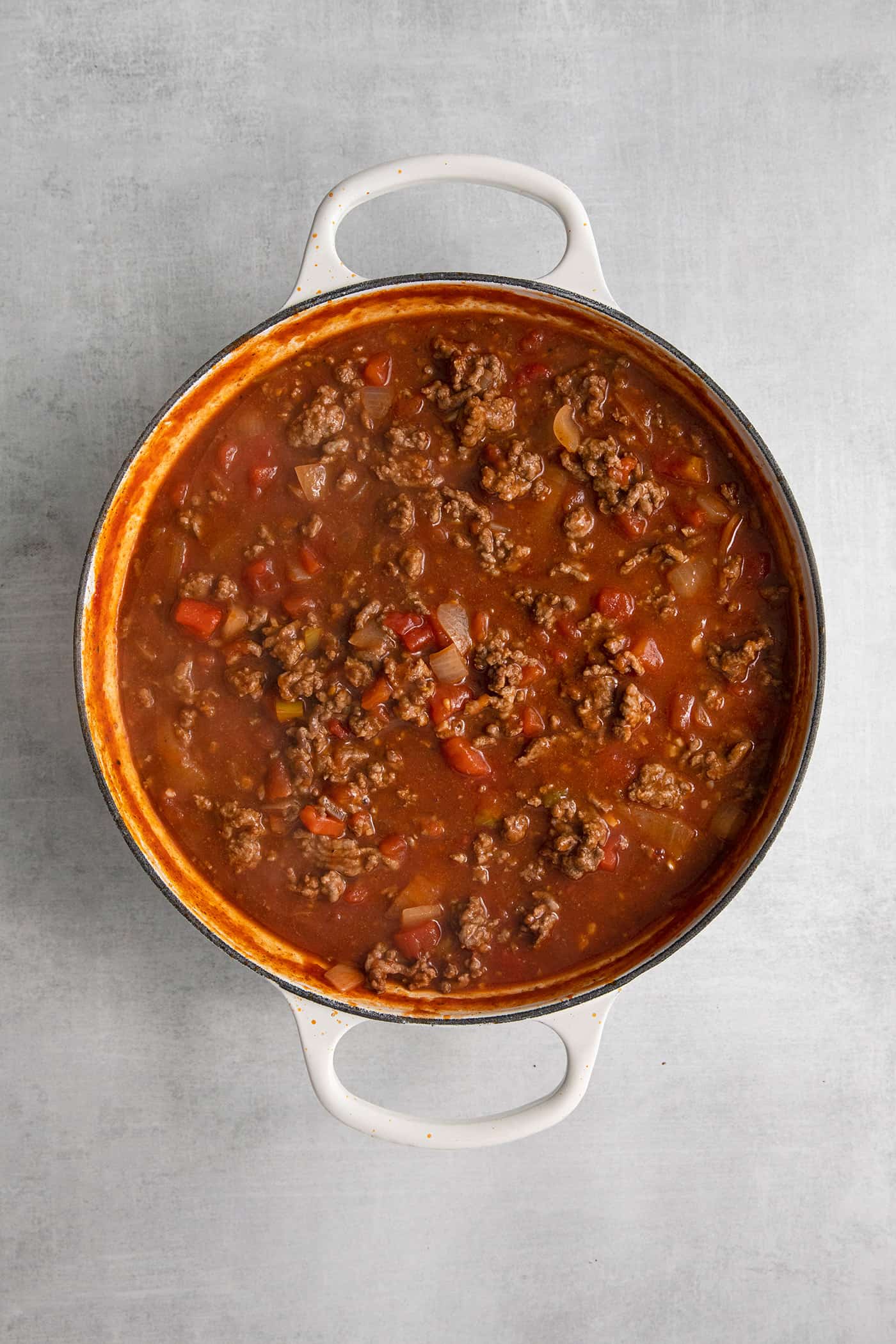 This Cheesy Beef Taco Dip is full of the beefy taco flavor you love, with ground beef, taco seasoning, Rotel, and loads of cheddar cheese. Ground beef, tomato sauce, and rotel in a skillet