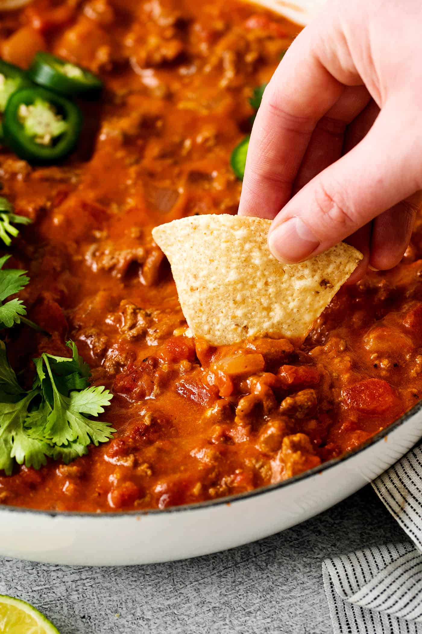 This Cheesy Beef Taco Dip is full of the beefy taco flavor you love, with ground beef, taco seasoning, Rotel, and loads of cheddar cheese. A tortilla chip digging into cheesy taco dip