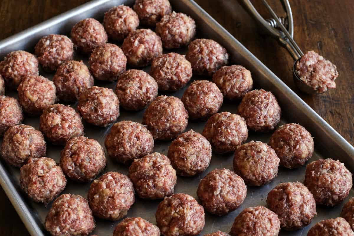 This easy Swedish meatballs recipe makes juicy, tender meatballs with a rich, creamy gravy. A homemade version of IKEA Swedish meatballs! Pork and beef meatballs portioned into rows on a baking sheet.