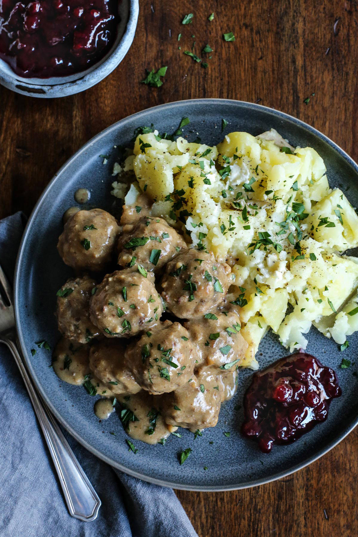 This easy Swedish meatballs recipe makes juicy, tender meatballs with a rich, creamy gravy. A homemade version of IKEA Swedish meatballs! Homemade IKEA Swedish meatballs served with potatoes and lingonberry jam on a stoneware plate.