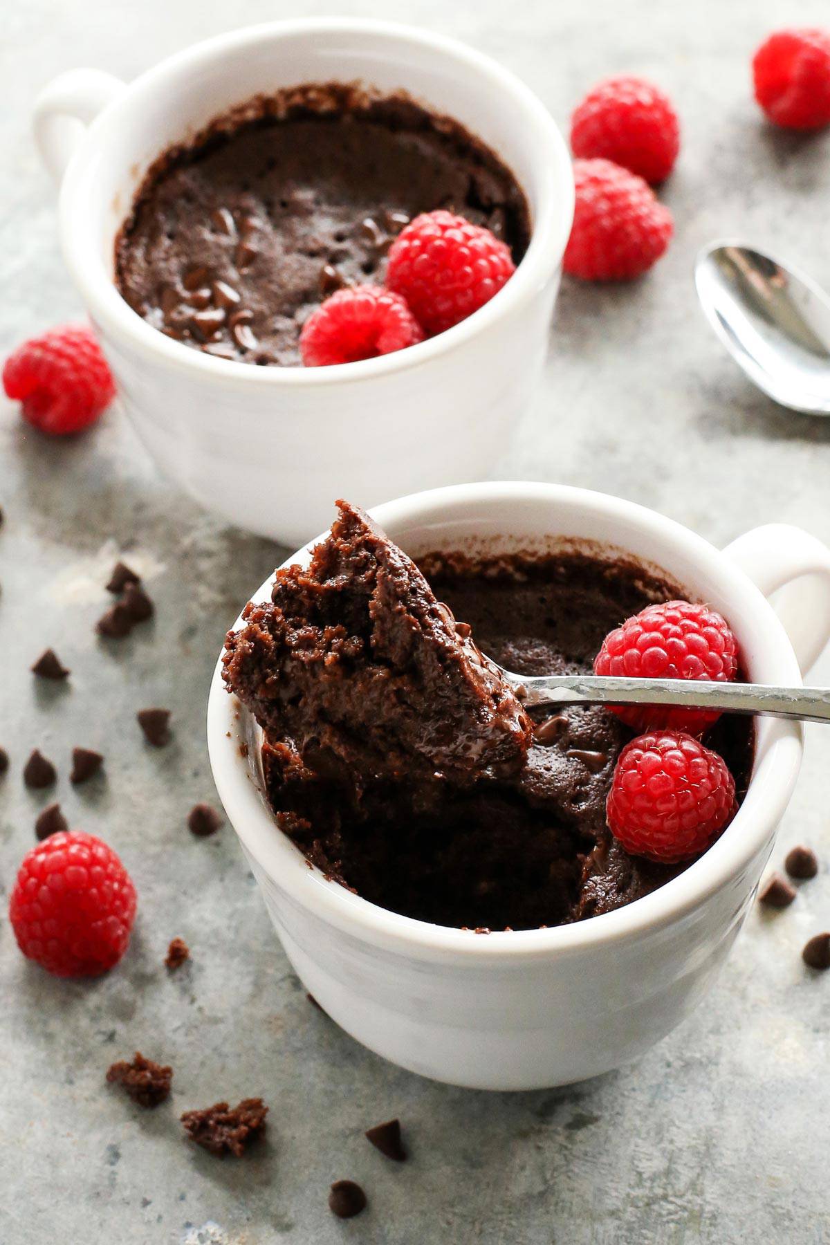 This gooey chocolate mug cake is fudgy, fluffy, and ready in minutes! Make this moist chocolate cake recipe with or without eggs. a spoon of chocolate cake out of a white mug