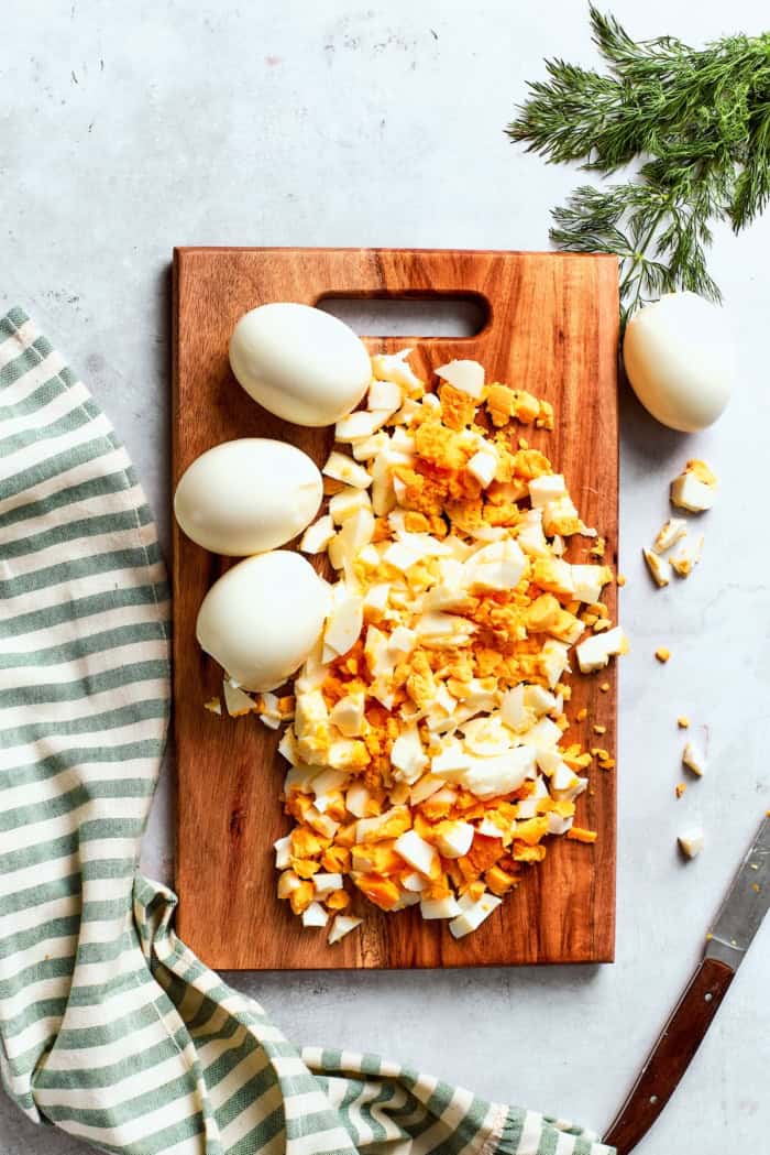 Creamy egg salad gets a fresh lift from bright herbs, making this egg salad sandwich a simple lunch that tastes anything but ordinary! Chopped eggs on wooden cutting board.