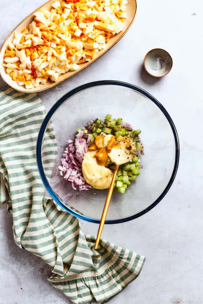Creamy egg salad gets a fresh lift from bright herbs, making this egg salad sandwich a simple lunch that tastes anything but ordinary! Ingredients for egg salad dressing in bowl with spoon.