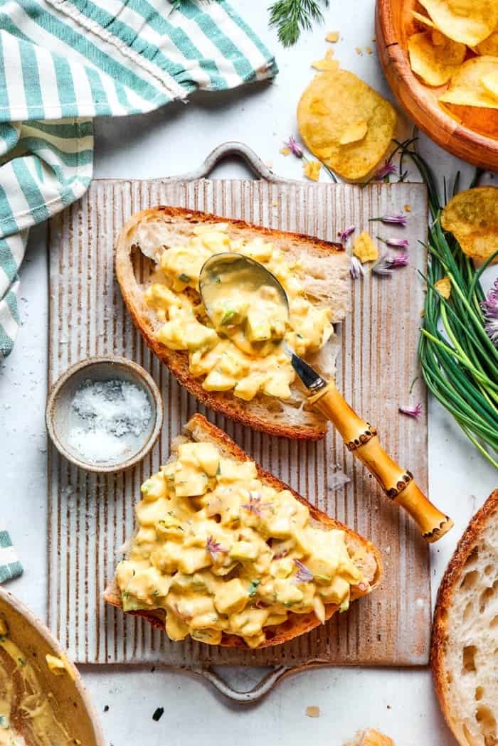 Creamy egg salad gets a fresh lift from bright herbs, making this egg salad sandwich a simple lunch that tastes anything but ordinary! Spoon set on slice of bread topped with creamy egg salad.