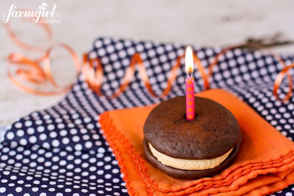 Whoopie Pies with Fluffy Peanut Butter Marshmallow Cream are the ultimate cake sandwich! It doesn't get much better than this classic peanut butter and chocolate combination. A whoopie pie with a pink candle on top.