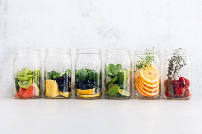Six delicious flavor ideas for making infused spa water at home. Put extra herbs and fruit to use and make staying hydrated so much tastier! Fruit and herbs added to jars for spa water
