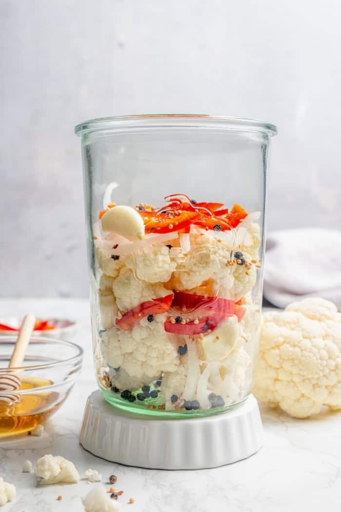 Cauliflower, red bell pepper, onion, and spices layered in large jar