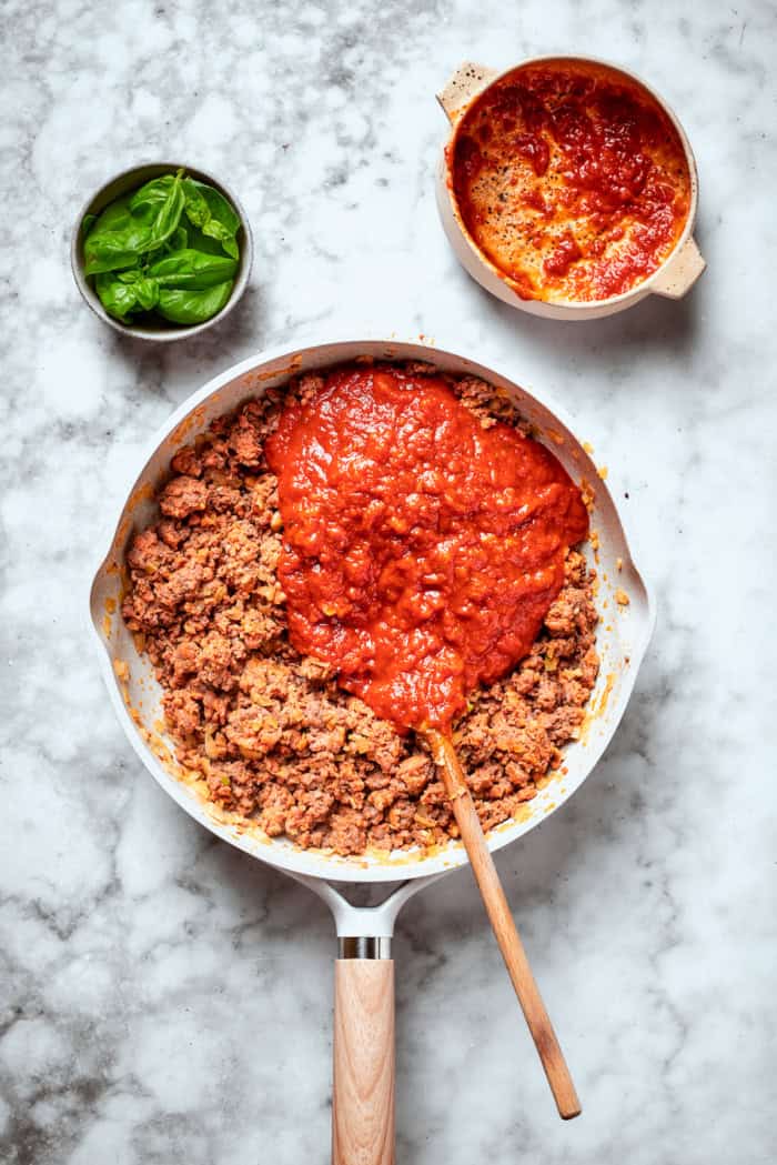Meaty sauce, super fun spaghetti noodles, and pockets of Cheesy Yum make this Spaghetti Casserole an instant hit with the whole family! Overhead view of marinara added to meat in skillet