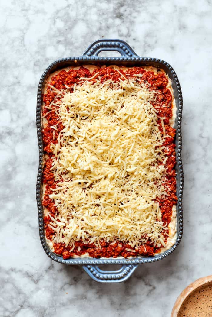 Meaty sauce, super fun spaghetti noodles, and pockets of Cheesy Yum make this Spaghetti Casserole an instant hit with the whole family! Overhead view of spaghetti casserole in baking dish before baking