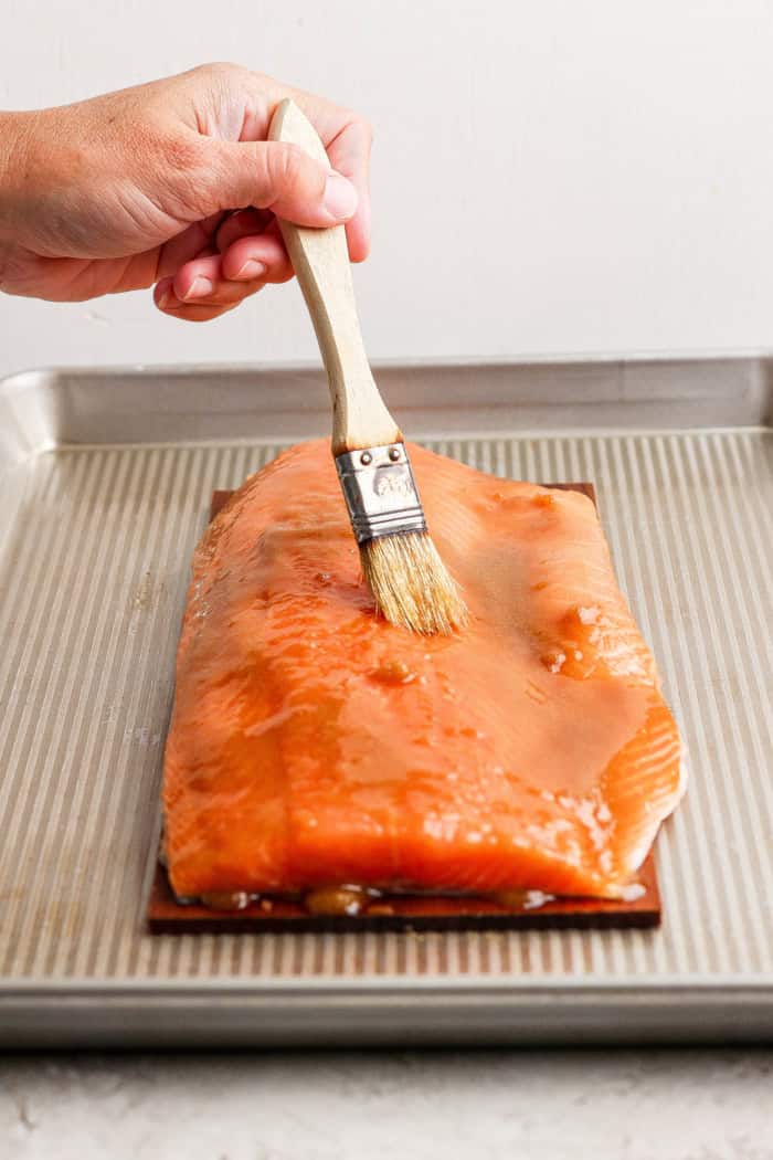 Brushing raw salmon with glaze on cedar plank