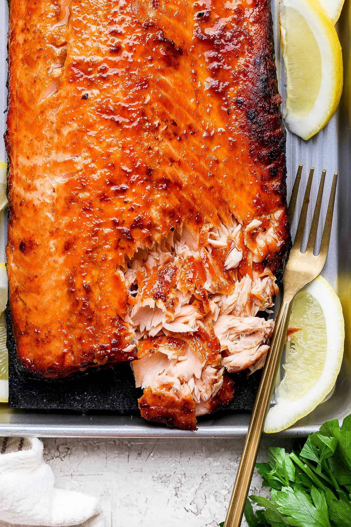 This Sweet and Smoky Grilled Salmon recipe is guaranteed to be perfectly moist, with a smoky maple brown sugar glaze that’s irresistible! Overhead view of sweet and smoky salmon with corner flaked to show texture